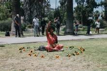 Schwarze Frau sitzt in Kreis von Sonnenblumen und hebt die rechte Faust