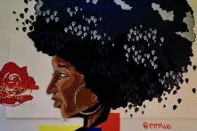 Wandbild einer Schwarzen Frau im Profil mit Afrofrisur, in und um den Haaren sind zahlreiche erhobene Fäuste zu sehen; links davon ist eine rote Rose abgebiledet, auf der "Rose City Justice" steht, signiert ist das Bild mit @empwo 