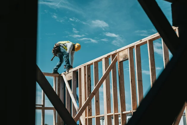 Ein Arbeiter mit Helm auf einem Holzgerüst