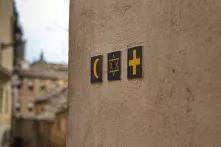 Halbmond, Davidstern und Kreuz an einer Hauswand