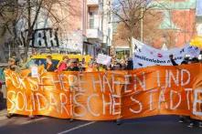 Demonstration in Berlin: Orangefarbener Banner mit der Aufschrift "Sichere Häfen und solidarische Städte"
