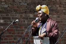 Foto von Emilene Wopana Mudimu mit einem Mikro in der einen und einem Blatt Papier in der anderen Hand