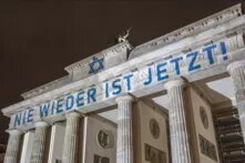 Das Brandenburger Tor in Berlin, auf dem "Nie wieder ist jetzt!" projiziert ist.