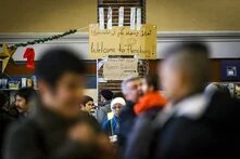 Mehrere Menschen in einer belebten Halle, im Hintergrund ein Schild mit „Welcome to Flensburg!“