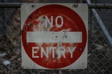 Rotes Einfahrtsverbotsschild mit der Aufschrift "No Entry", das an einem Zaun befestigt ist