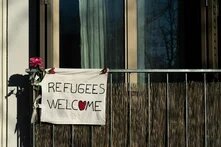 An einem Balkon hängt ein Transparent mit der Aufschrift "Refugees Welcome"