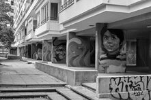 Schwarz-Weiß Foto einer Straße in Kreuzberg mit Wandgemälden, auf denen die Gesichter von unterschiedlichen Kindern sehen sind