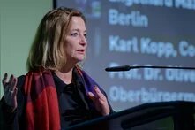 Petra Bendel steht an einem Rednerpult und spricht ins Mikrofon