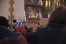 Auf einer Demonstration wird ein Schild mit der Aufschrift "Demokratie retten" hochgehalten
