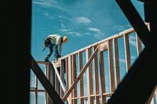 Ein Arbeiter mit Helm auf einem Holzgerüst