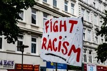 Auf einem weißen Transparent steht in roter Schrift "Fight Racism"