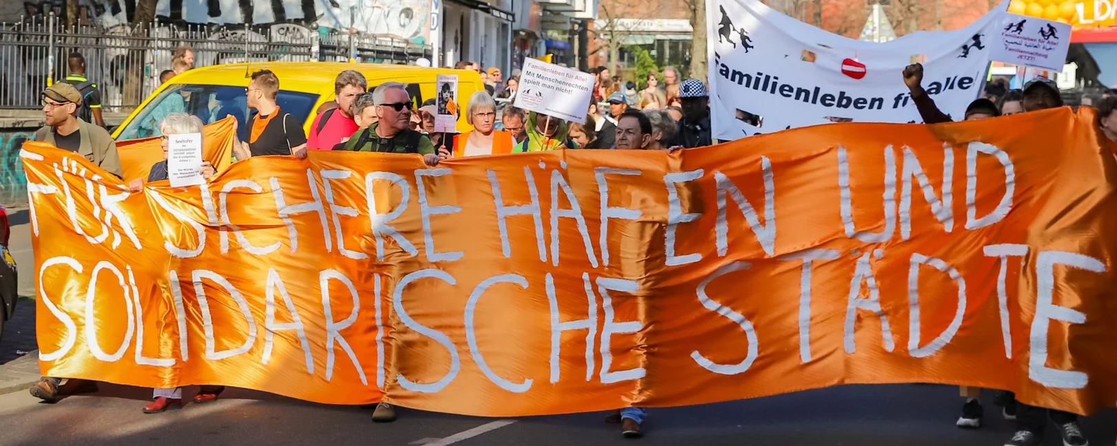 Demonstration in Berlin: Orangefarbener Banner mit der Aufschrift 