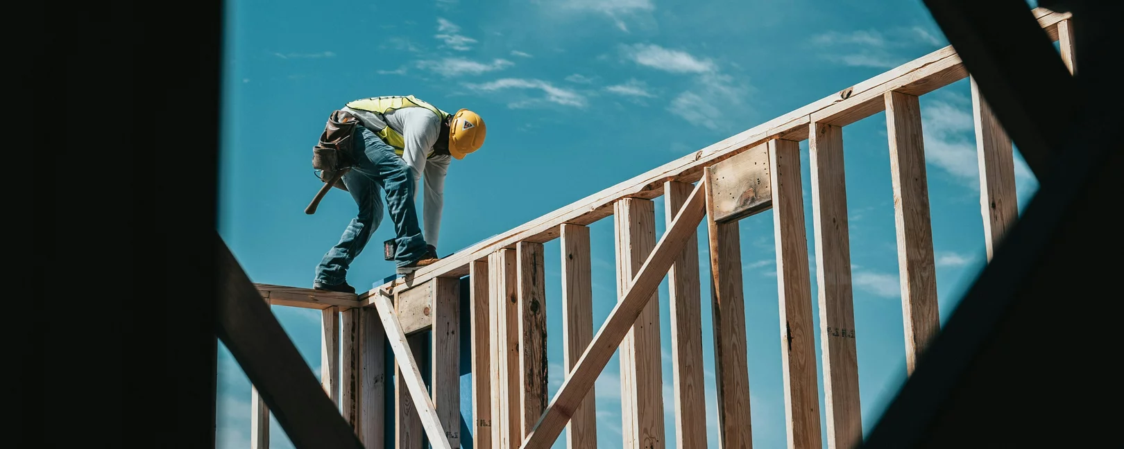 Ein Arbeiter mit Helm auf einem Holzgerüst