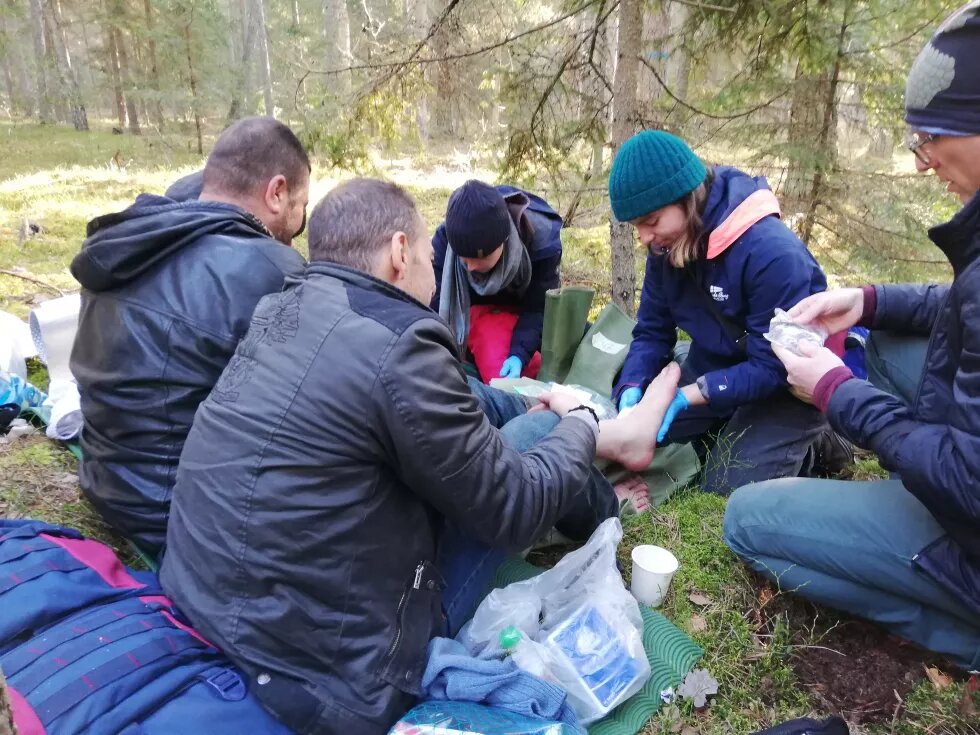 Helfer*innen versorgen den Fuß eines Geflüchteten im Wald