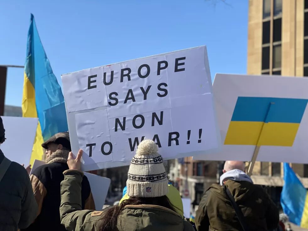 Demonstration in Solidarität mit der Ukraine in den USA: Zu sehen sind zwei ukrainische Flaggen und ein Schild mit der Aufschrift "Europe says non to war!!"