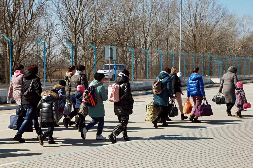 Eine Gruppe geflüchteter Frauen und Kinder läuft mit Gepäck eine Straße am Grenzübergang Palanca-Maiaki-Udobnoe zwischen Moldawien und der Ukraine