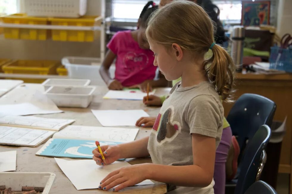 Zwei Kinder sitzen in der Schule an einem Tisch und malen