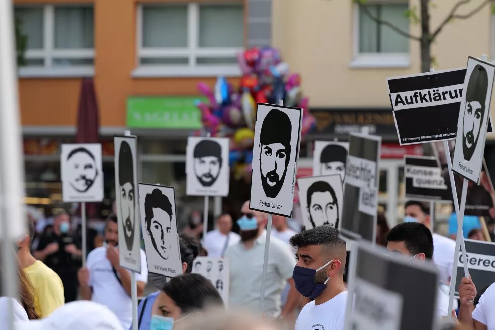 Gedenkkundgebung für die Opfer des rassistischen Anschlags in Hanau, Menschen halten Schilder mit den Gesichtern und Namen der Opfer hoch