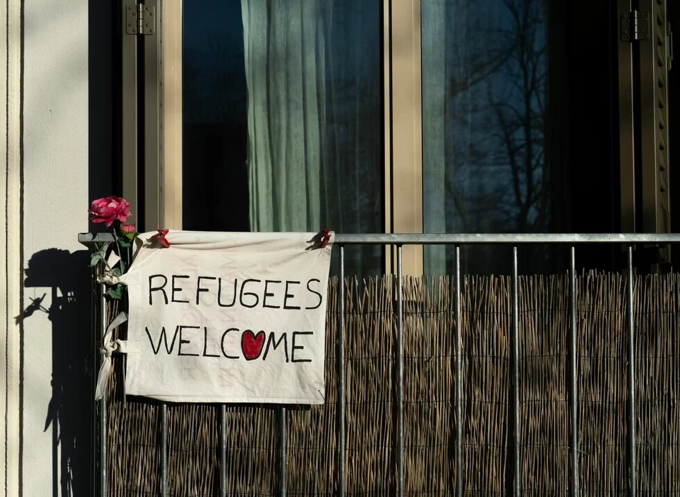 An einem Balkon hängt ein Transparent mit der Aufschrift "Refugees Welcome"