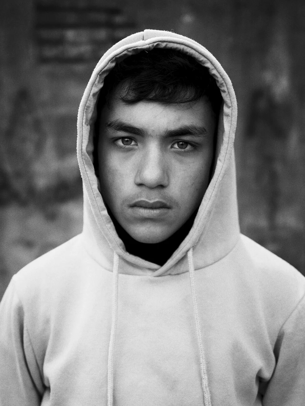 Schwarz-Weiß Portrait eines Jugendlichen, der einen Kapuzenpulli trägt und in die Kamera schaut