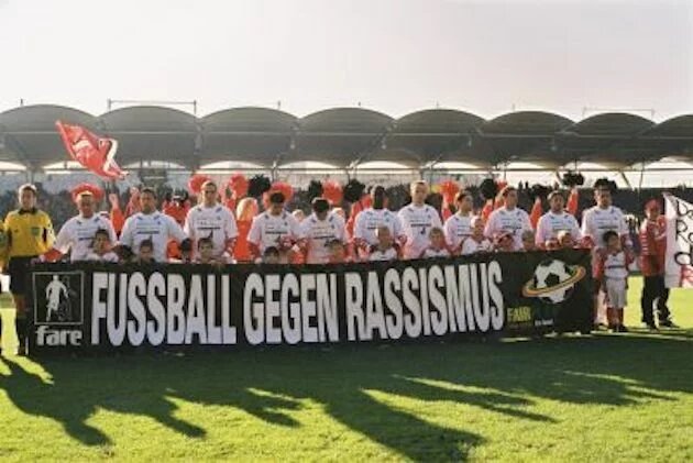 Fußballmannschaft mit "Fußball gegen Rassismus" Banner