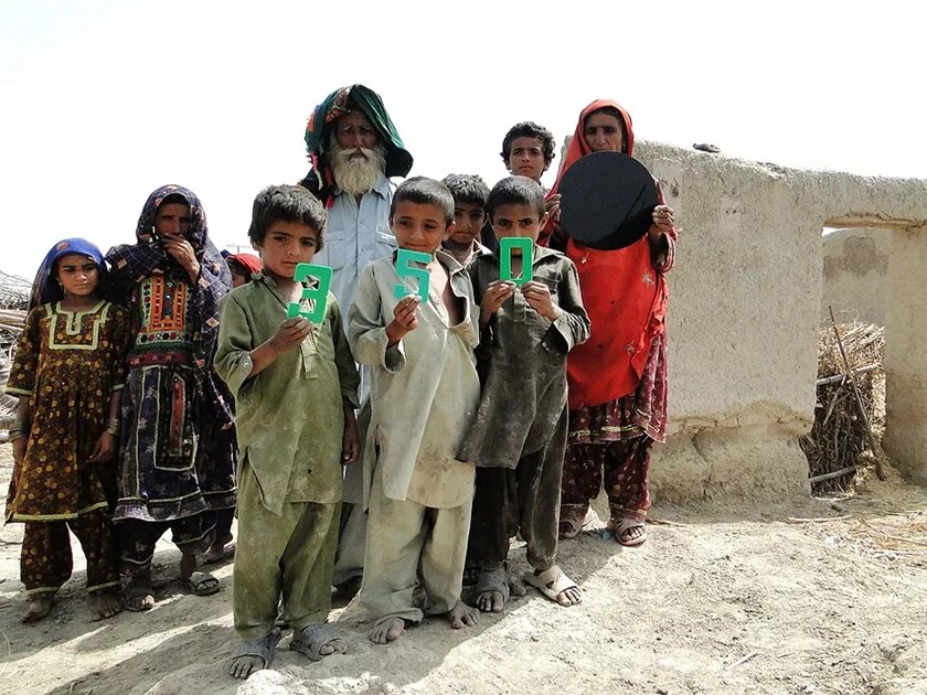 A Pakistani family, victims of a huge flood holding up the letters 350 – which stand for one of the climate goals: 350ppm