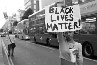 Person hält Schild mit Aufschrift "Black Lives Matter!" in London 2016
