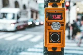 Knopf an einer Ampel, über dem ein Aufkleber mit der Aufschrift "push to reset the world" klebt