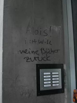 Ein Klingelbrett über dem die Worte "Alois ich will meine Bücher zurück" geschrieben stehen